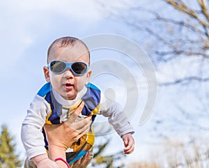 Nice baby with blue googles raised in air