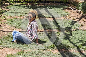 Nice beautiful middle age lady sitting on a timo grass enjoying the nature in outdoor leisure activity, summer and sunny day photo