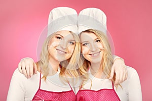 Pretty blonde twins posing for double portrait as bakers