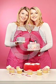 Pretty blonde twins with desserts and cakes on pink