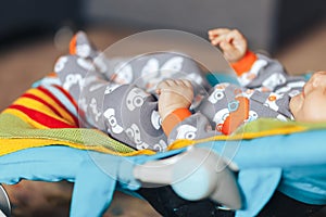 nice blue eyed Baby child relaxing on a sunbed or a deck chair colored bouncer at home