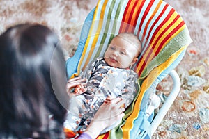 nice blue eyed Baby child relaxing on a sunbed or a deck chair colored bouncer at home