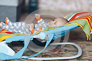 nice blue eyed Baby child relaxing on a sunbed or a deck chair colored bouncer at home