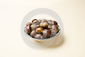 A nice bowl of chestnuts on beige background