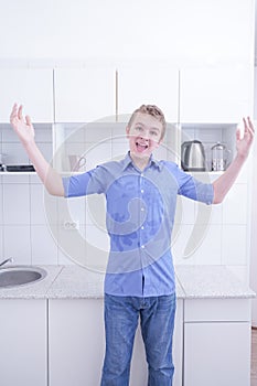 Nice boy in blue shirt with emotions on kitchen alone