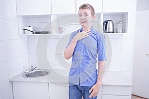 Nice boy in blue shirt with emotions on kitchen alone