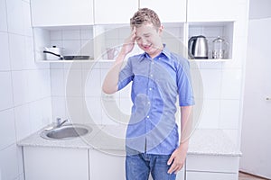 Nice boy in blue shirt with emotions on kitchen alone