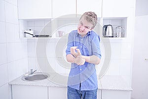Nice boy in blue shirt with emotions on kitchen alone