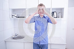 Nice boy in blue shirt with emotions on kitchen alone