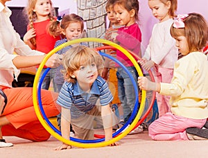 Nice boy play with hoops in kindergarten goup