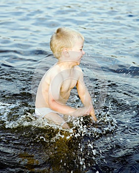 Nice boy swashes in water of the Baltic sea