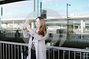 Nice businesswoman making selfie by smartphone near valise and airport.