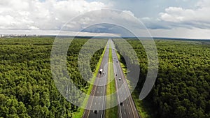 Nice cinematic aerial view of highway in the middle of the day cloudy weather. A lot of cars passing from one city to