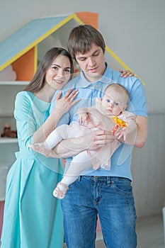 Nice close-knit family of mom, dad and daughter posing in their white room