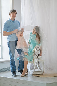 Nice close-knit family of mom, dad and daughter posing in their white room photo