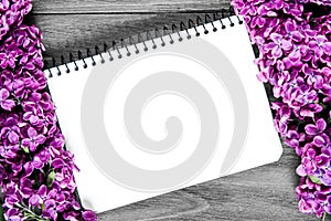 Nice composition of a blank notebook and lilac flowers on the grey wooden surface