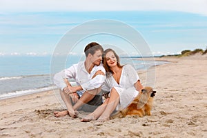 Nice couple of young lovers with a dog relax on the beach