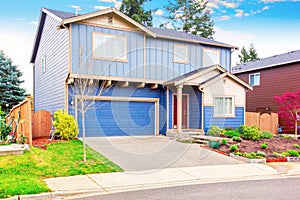 Nice curb appeal of blue house with front garden and garage with driveway