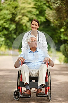 Nice day to be out and about. a female doctor taking her senior patient for an outing in his wheelchair.