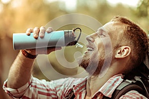 Nice delighted bearded man holding a thermos bottle