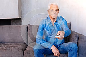 Nice elderly man holding a remote control
