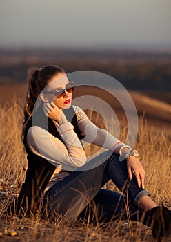 Nice,excellent,awesome girl,woman,model sits on the hill with beautiful,wonderful view.Luxury girl with sunglasses watching sunset