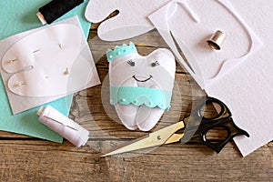 Nice felt tooth fairy pillow, paper template, felt sheets and scraps, scissors, thread on vintage wooden background