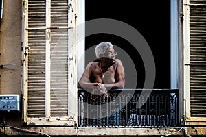 Nice, France - August 6, 2011: a shirtless old black man looks out the window at Nice in Provence, France