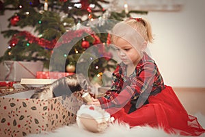 Nice girl enjoying plenty of gifts under garnished christmas tree
