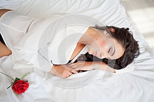 Girl in lingerie lying on a bed with a rose