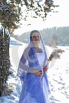 Vertical portrait against the background of the winter landscape of a beautiful young brunette in a long white dress and a