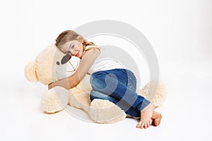 Nice girl lying on floor with toy bear hugging it.