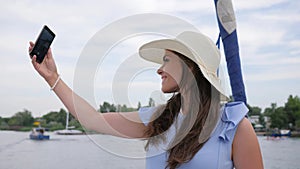 Nice girl make selfie on yacht, android in hand women, holiday pictures, woman do pictures on your mobile phone in open