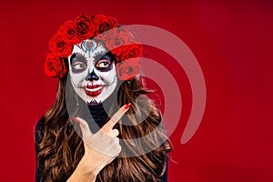 nice glamorous beautiful mexican dark brown eyes woman ready to Santa Muerte day pointing at copyspace