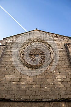 Nice gothic rose window on a stone wall of a church in sunny day. Galician city of Lugo, Spain