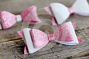 Nice hair bows accessories made of light pink and white felt with sequins. Hair bows for girls on an old wooden table. Closeup