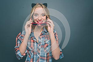 Nice and happy person is wearing grey with red shirt and a kitten ear on her head. Also she is putting on her glasses