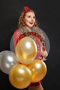 Nice happy surprised woman with makeup and hairstyle wearing red shiny sequins dress holding party balloons, surprise, gifts