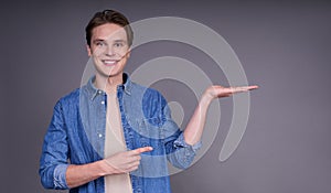 A nice happy young man in a denim shirt, posing with his hand