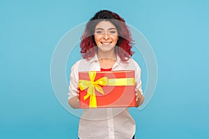 Nice holiday present. Portrait of cheerful hipster woman with fancy red hair holding gift box and smiling