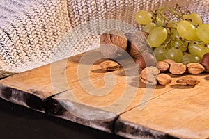 A nice image of mixed nuts and grapes on a wooden surface.