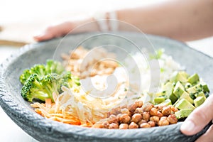 Nice image of a woman serving fresh salad in a buddha bowl.