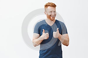 Nice job man, like it. Pleased good-looking happy male friend with ginger hair and brislte, showing thumbs up and