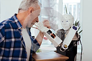 Nice joyful man looking at the robot