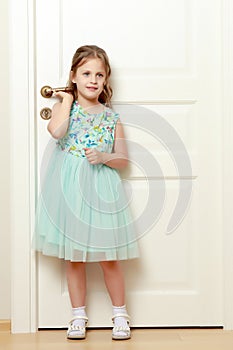 A little girl is standing by the door.