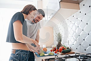 Nice looking interior. Young couple in the modern kitchen at home at their weekend time in the morning