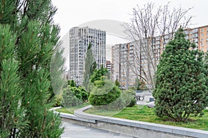 Nice modern leisure city park with benchs surrounded high-rise building.