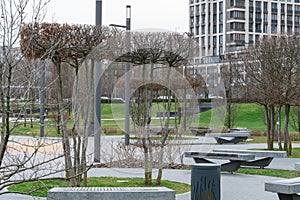 Nice modern leisure city park with benchs surrounded high-rise building.