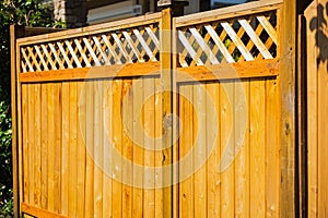 Nice new wooden fence around house. Wooden fence with toppers. Red wood fence with lattice panels