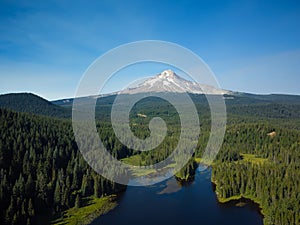 Nice panoramic shot. Among the green shores is a small dark blue lake. A high snow-covered mountain, a dormant volcano in the